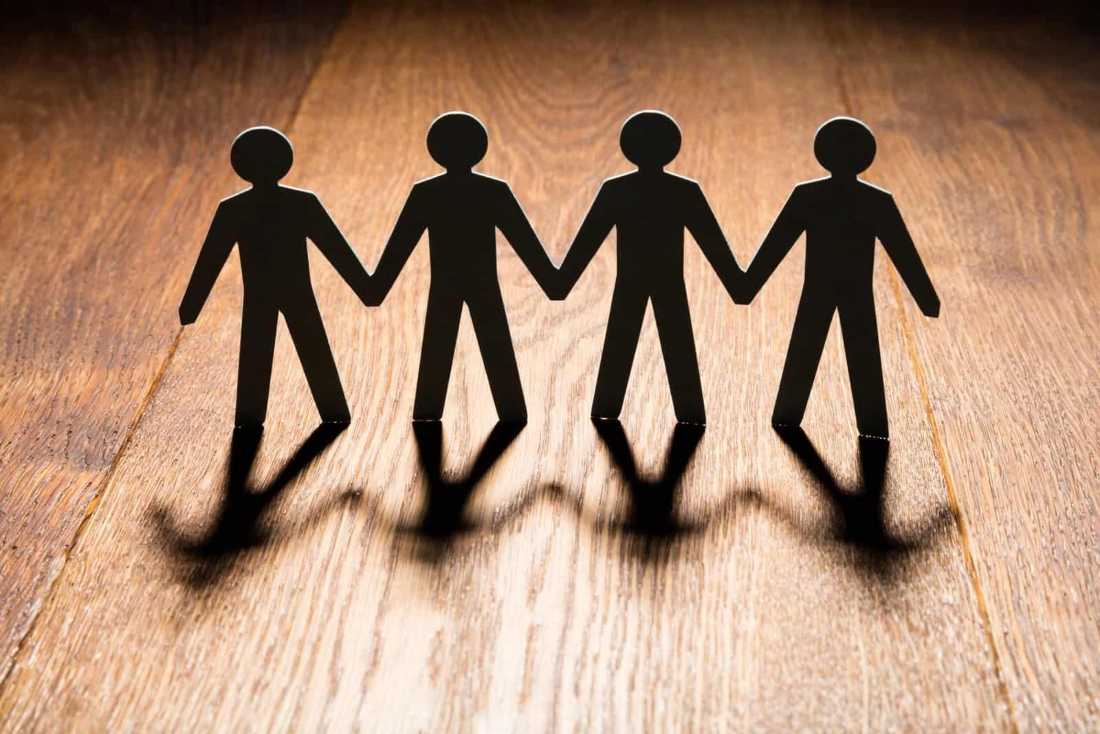 Siluetas de figuras humanas unidas sobre madera.